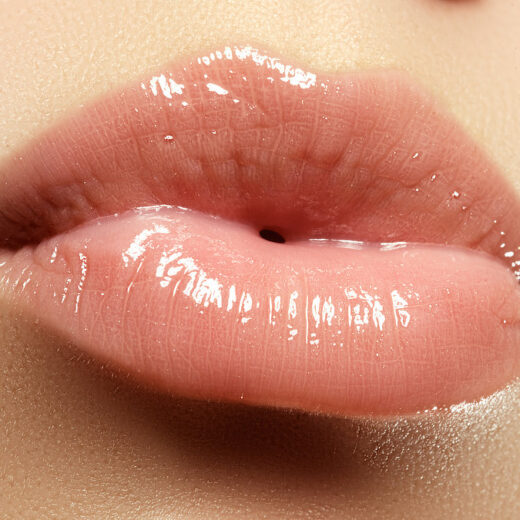 Glossy, pink lips close-up, with visible texture and shine.